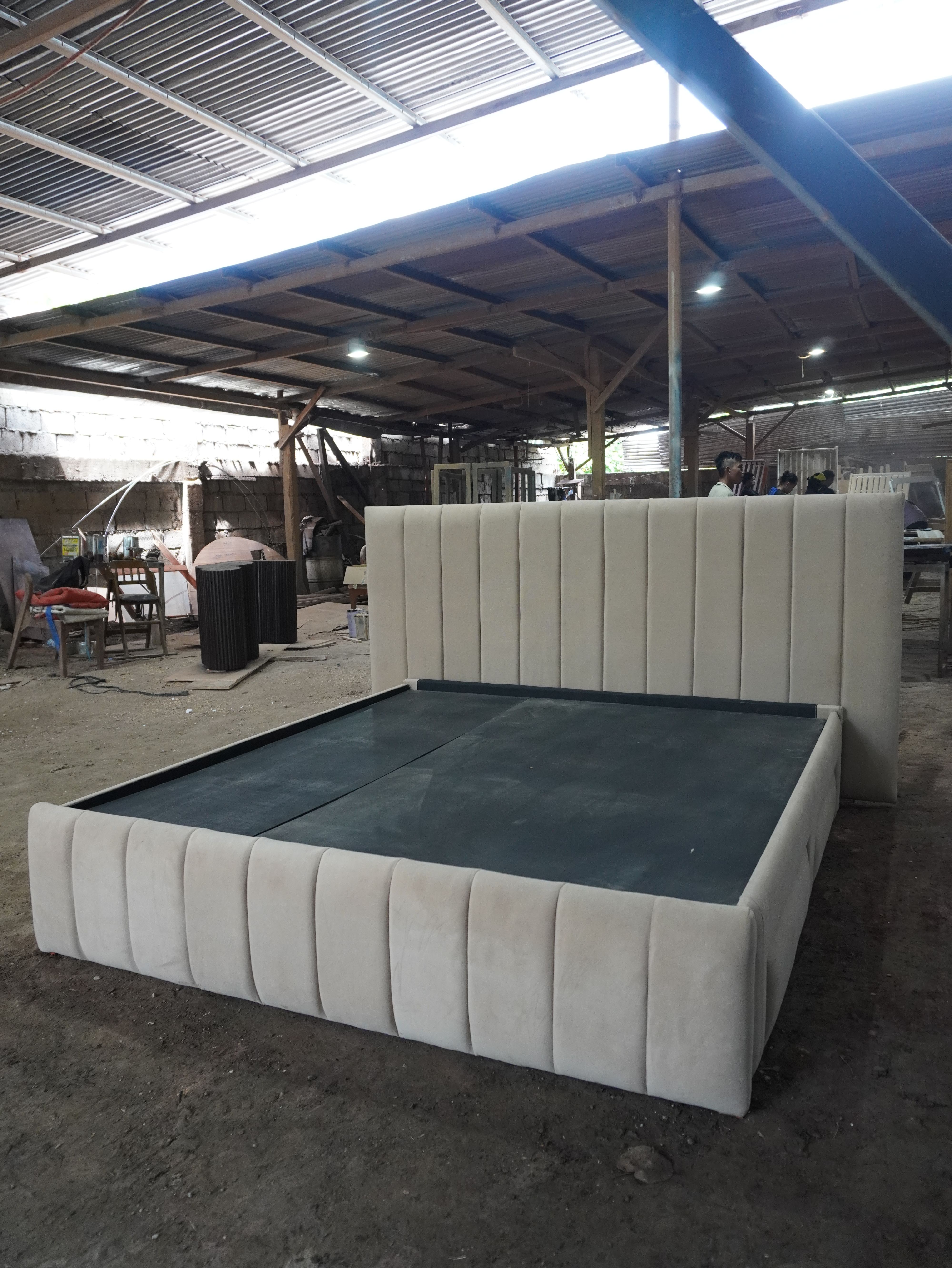 A calm, modern storage bed in soft sand-beige fabric, with an oversized vertical channel headboard, a matching channel footboard, and four upholstered side drawers that blend into the frame.