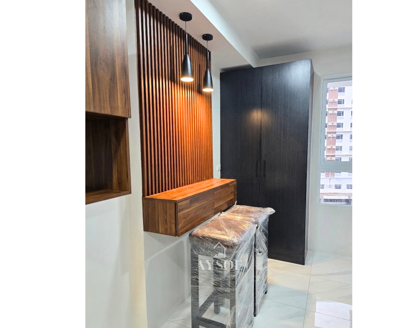 A compact walnut-finish kitchenette with upper and lower cabinets, plus a floating bar counter with a fluted wood wall panel and pendant lights. Made for condos and studio units.