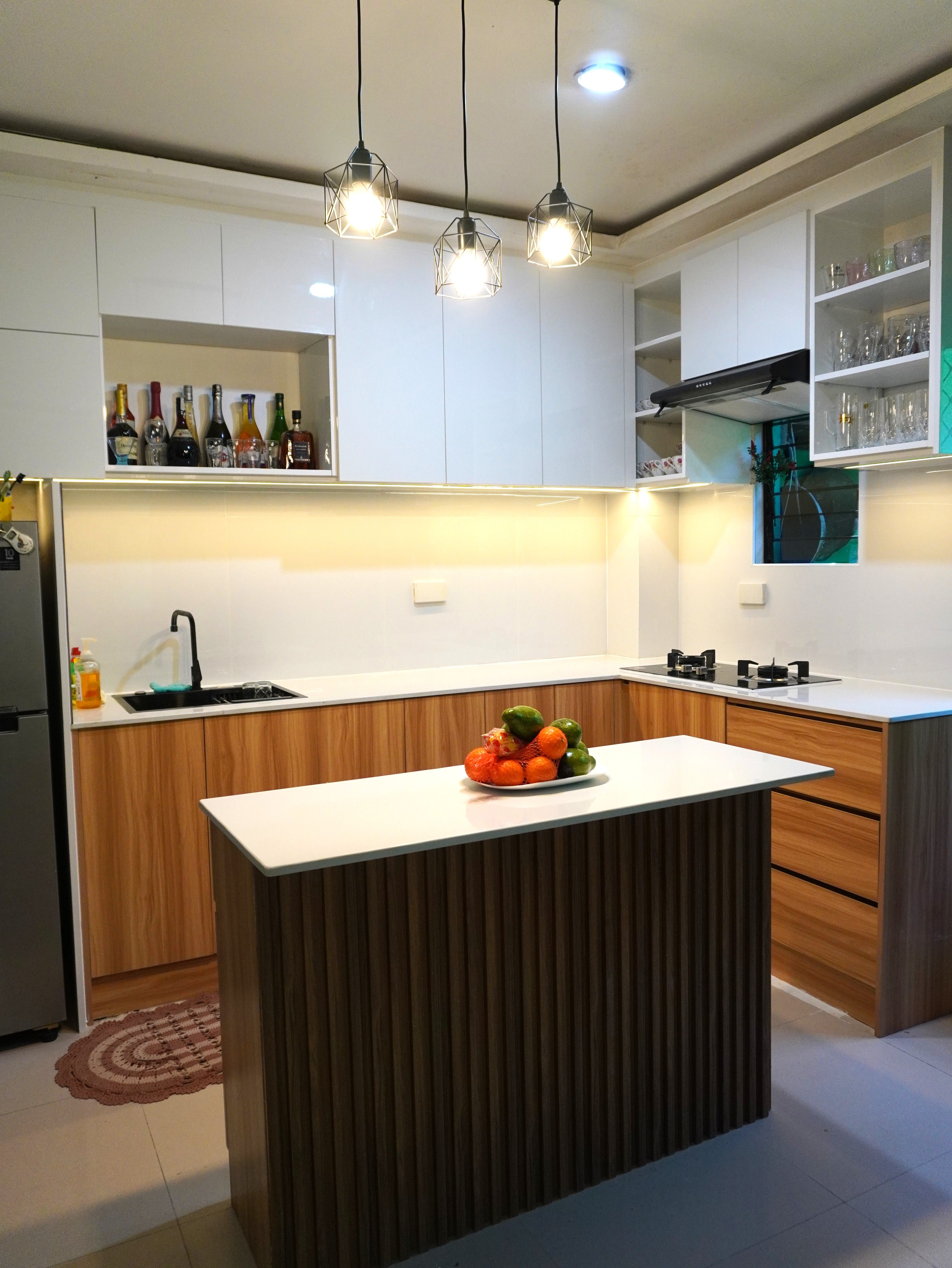 Custom-built kitchen cabinets with glossy white uppers, warm wood-grain base cabinets, and a fluted-panel island, designed for smart storage and a warm, modern look.