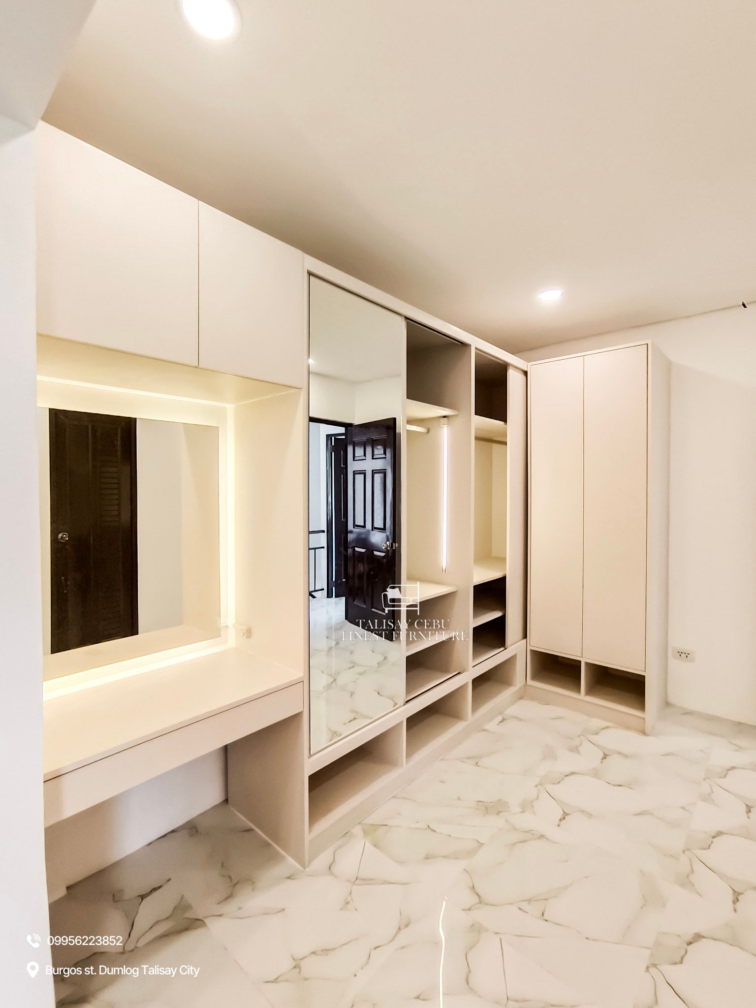 a custom floor-to-ceiling cream wardrobe with sliding mirror doors, open shoe cubbies, and a built-in vanity with drawer and overhead storage.