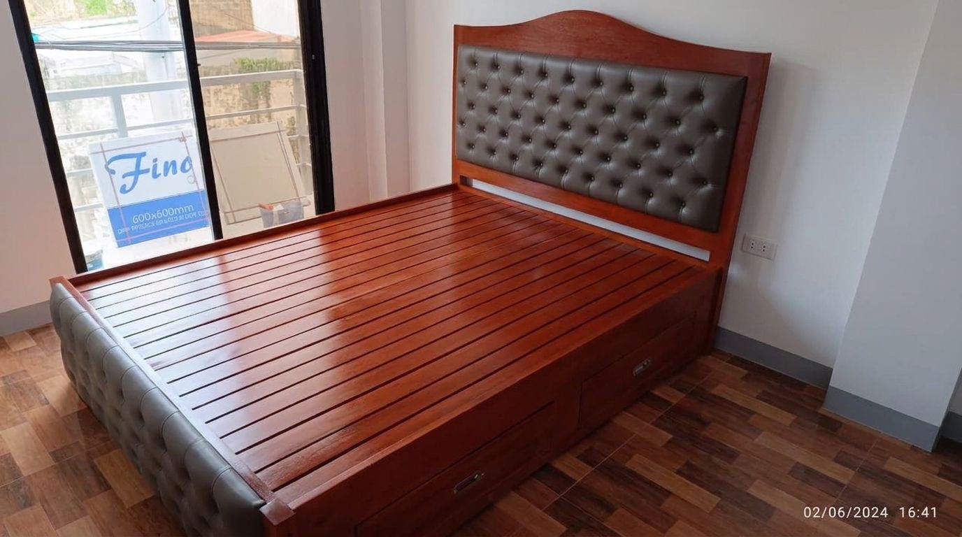 A solid wood bed in a rich glossy cherry finish, with an arched headboard, taupe button-tufted leatherette panels on the headboard and footboard, a slatted base, and built-in side drawers.