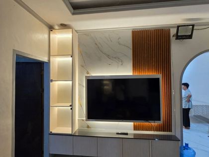 Modern TV feature wall with warm ambient lighting, a marble-look backdrop, wood slat accents, and sleek floating storage cabinets.
