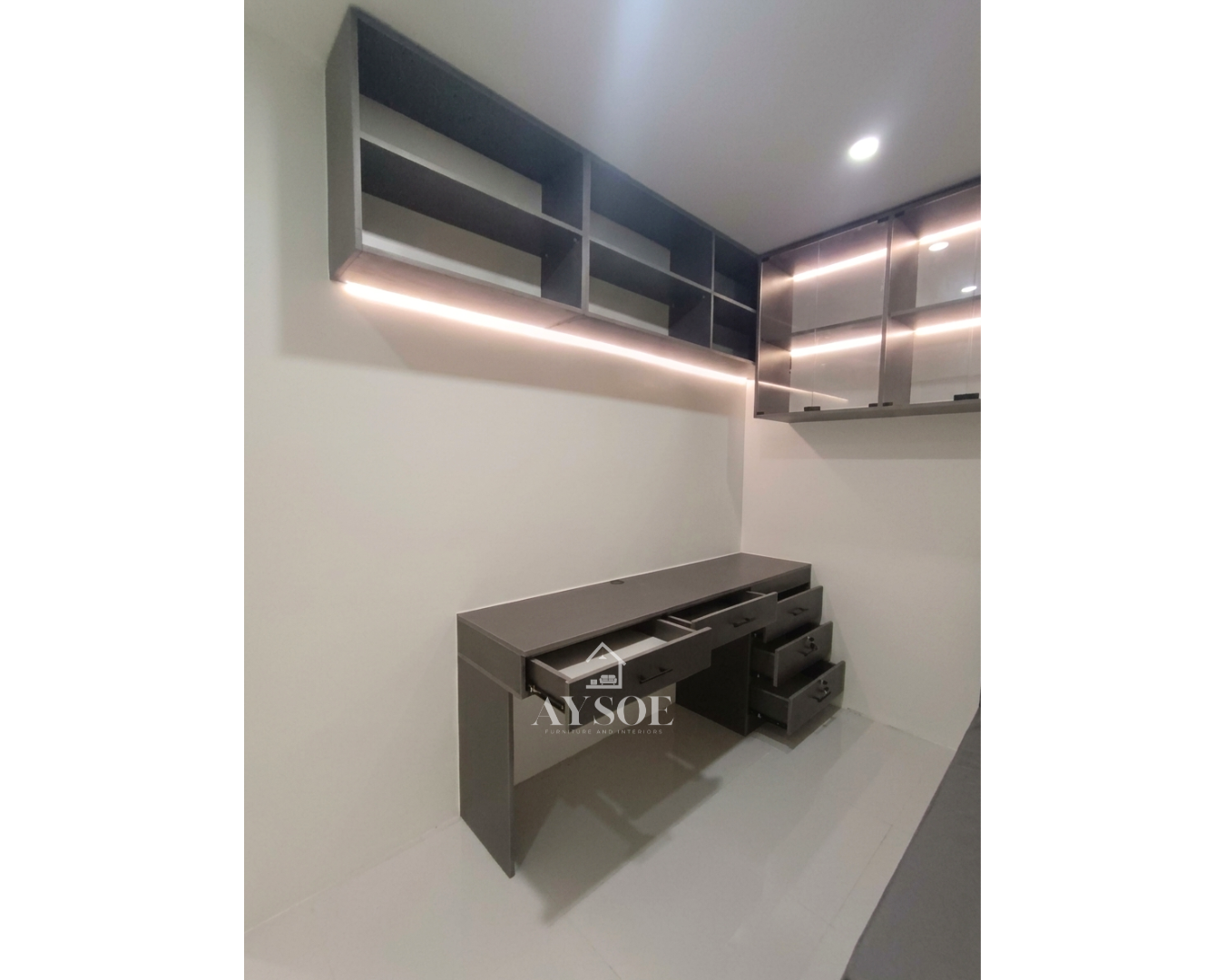 A compact charcoal-grey home office set with a built-in desk, wall-mounted shelves, lighted glass display cabinets, and a cushioned bench. Great for small rooms, studies, and work-from-home spaces.