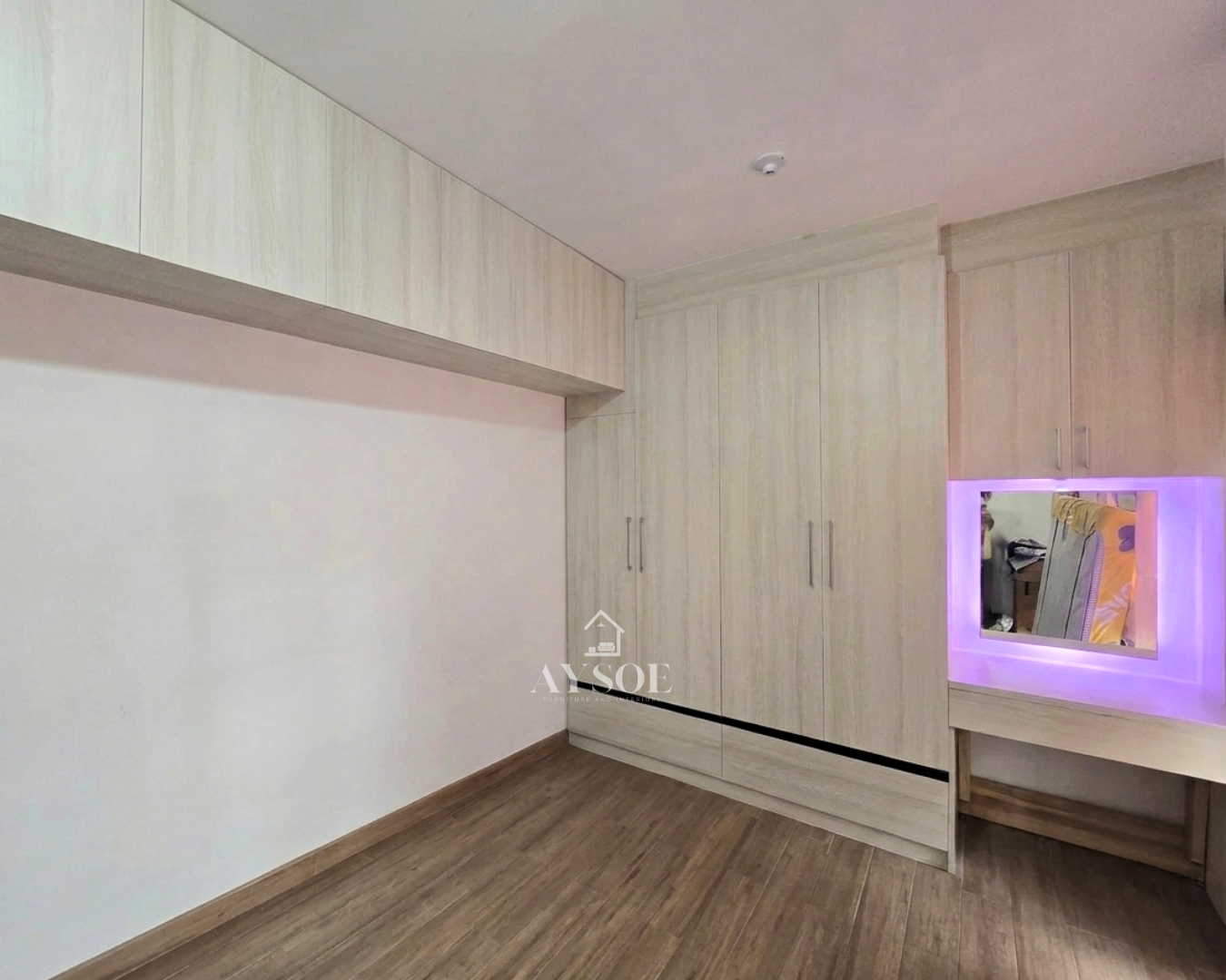 A custom light oak bedroom set with a tall four-door wardrobe, two bottom drawers, overhead cabinets, and a built-in vanity with an LED mirror. Lots of storage in one clean design.