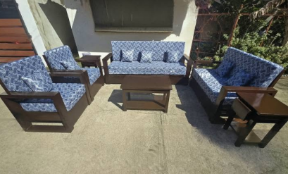 A matching dark wood, two-tiered center table sits in the middle. Two matching square dark wood side tables are placed in the rear corners between the sofas.