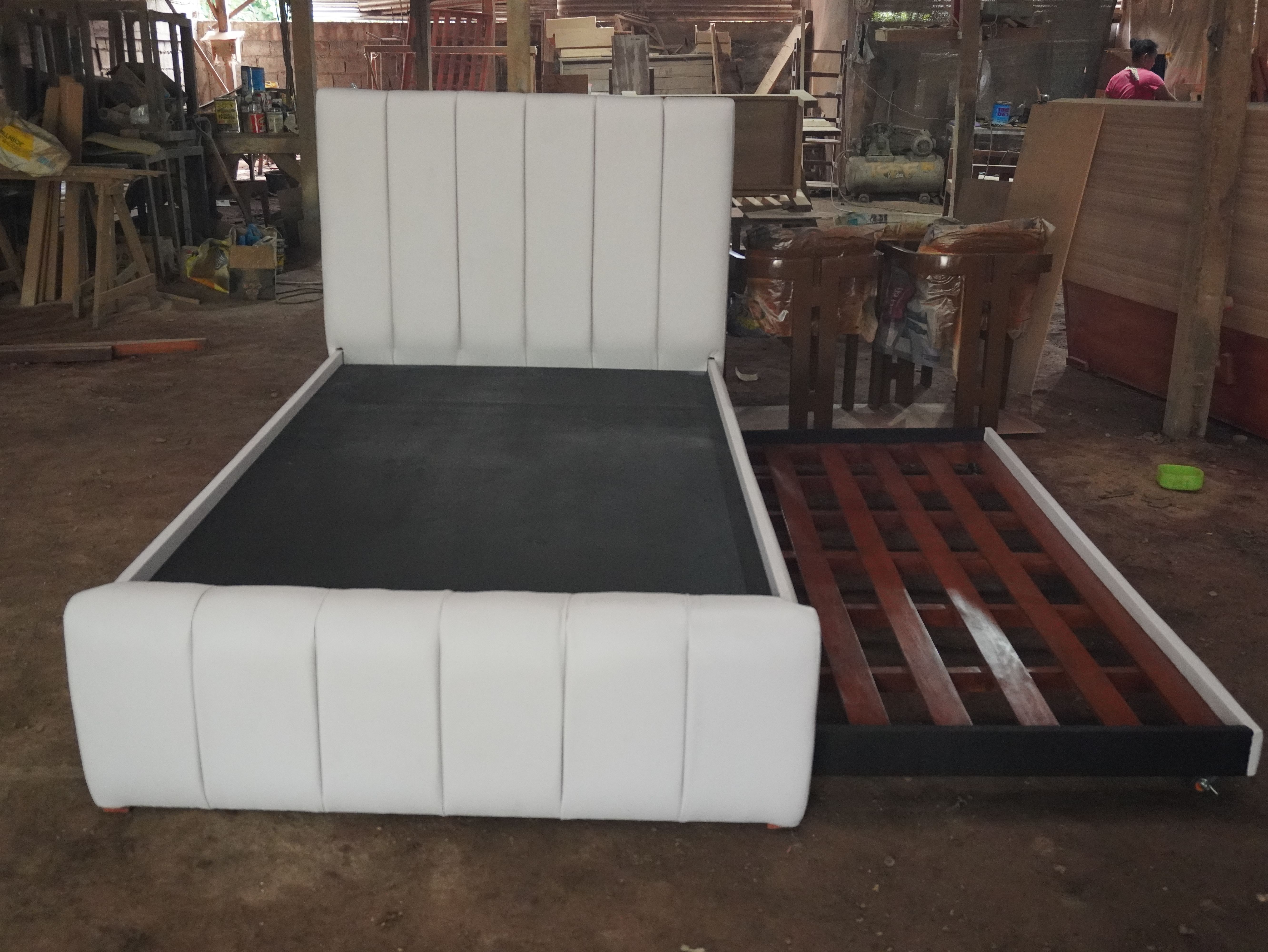 A clean white leatherette bed with a vertical channel headboard and footboard, plus a hidden pull-out bed on wheels. The pull-out can be set to slide out from either the left or right side to suit your room.