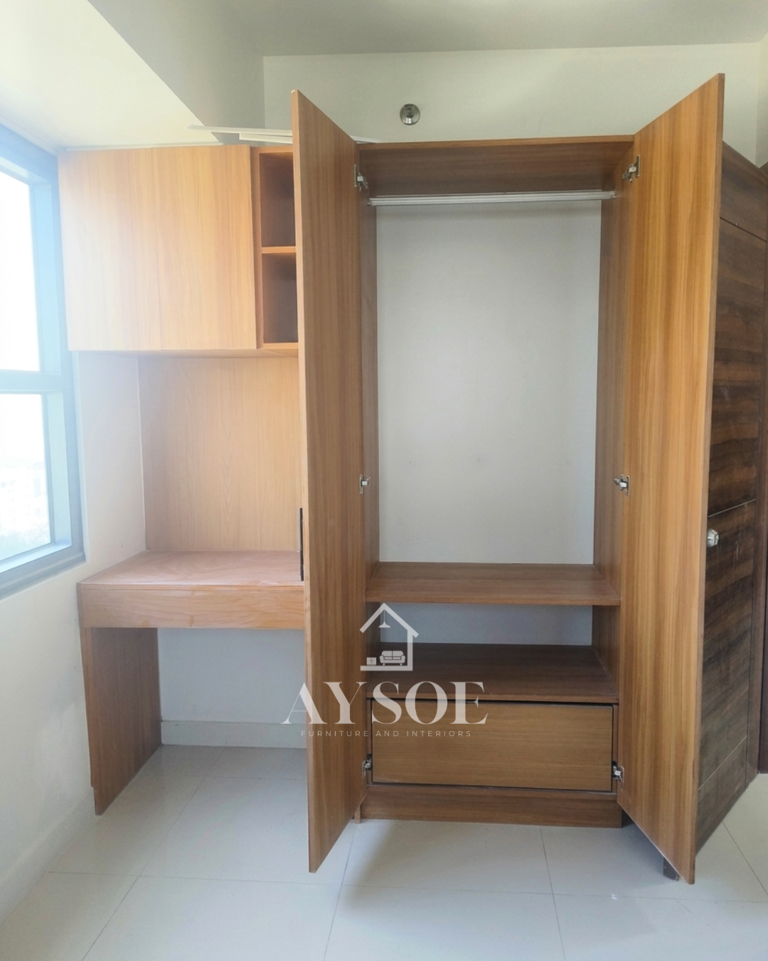 A custom honey oak wardrobe with a hanging rod, shelf, and pull-out drawer, plus a built-in study desk with overhead cabinets. Complete storage and a work spot for small rooms.