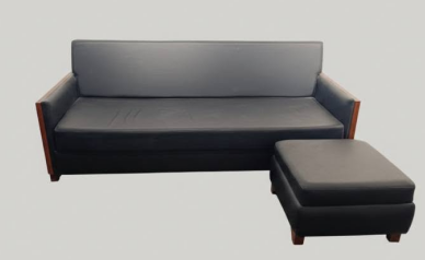 A large, matching rectangular upholstered ottoman is placed in front of the right side of the sofa, creating a versatile chaise-style extension or separate footrest.