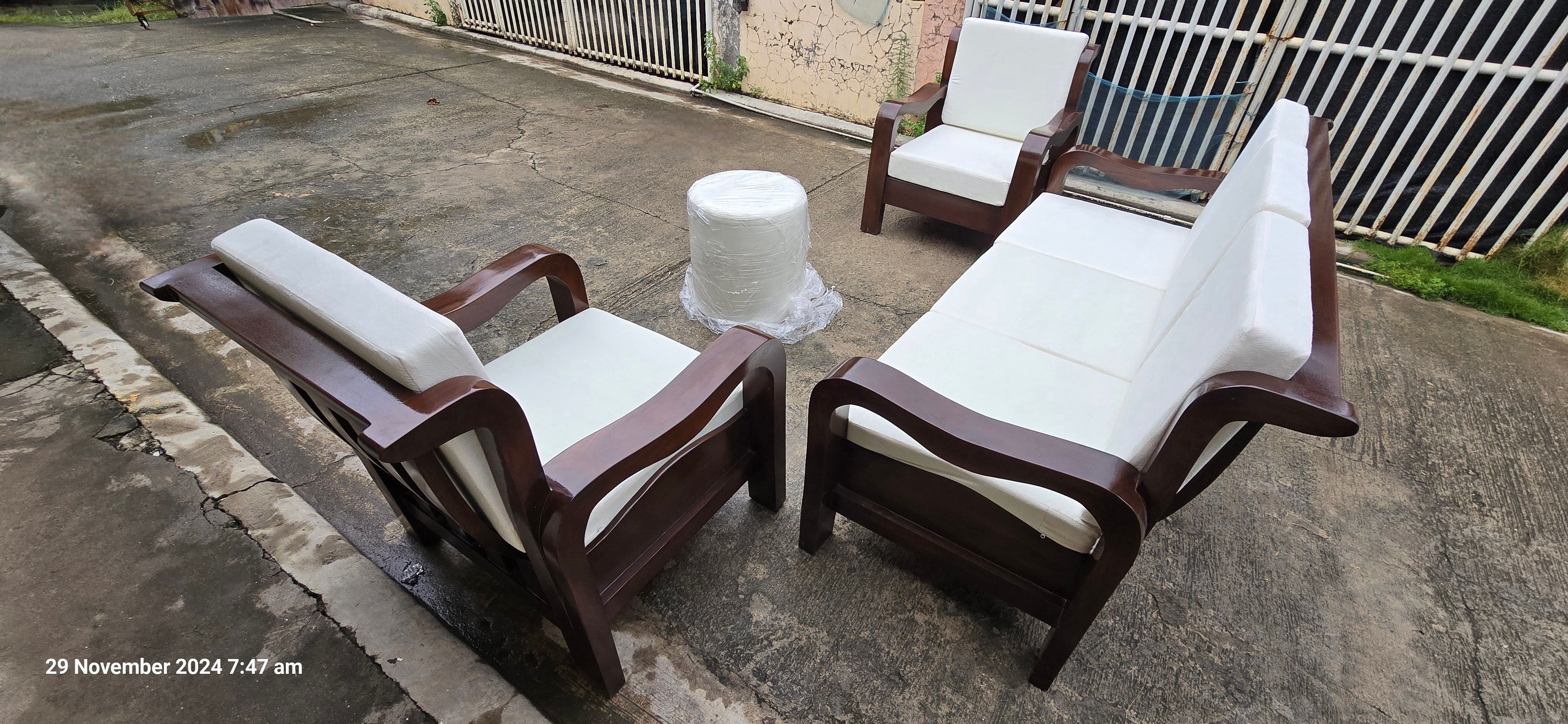 A cylindrical, fully upholstered white round ottoman sits directly in the center, functioning as a modern coffee table or footrest.