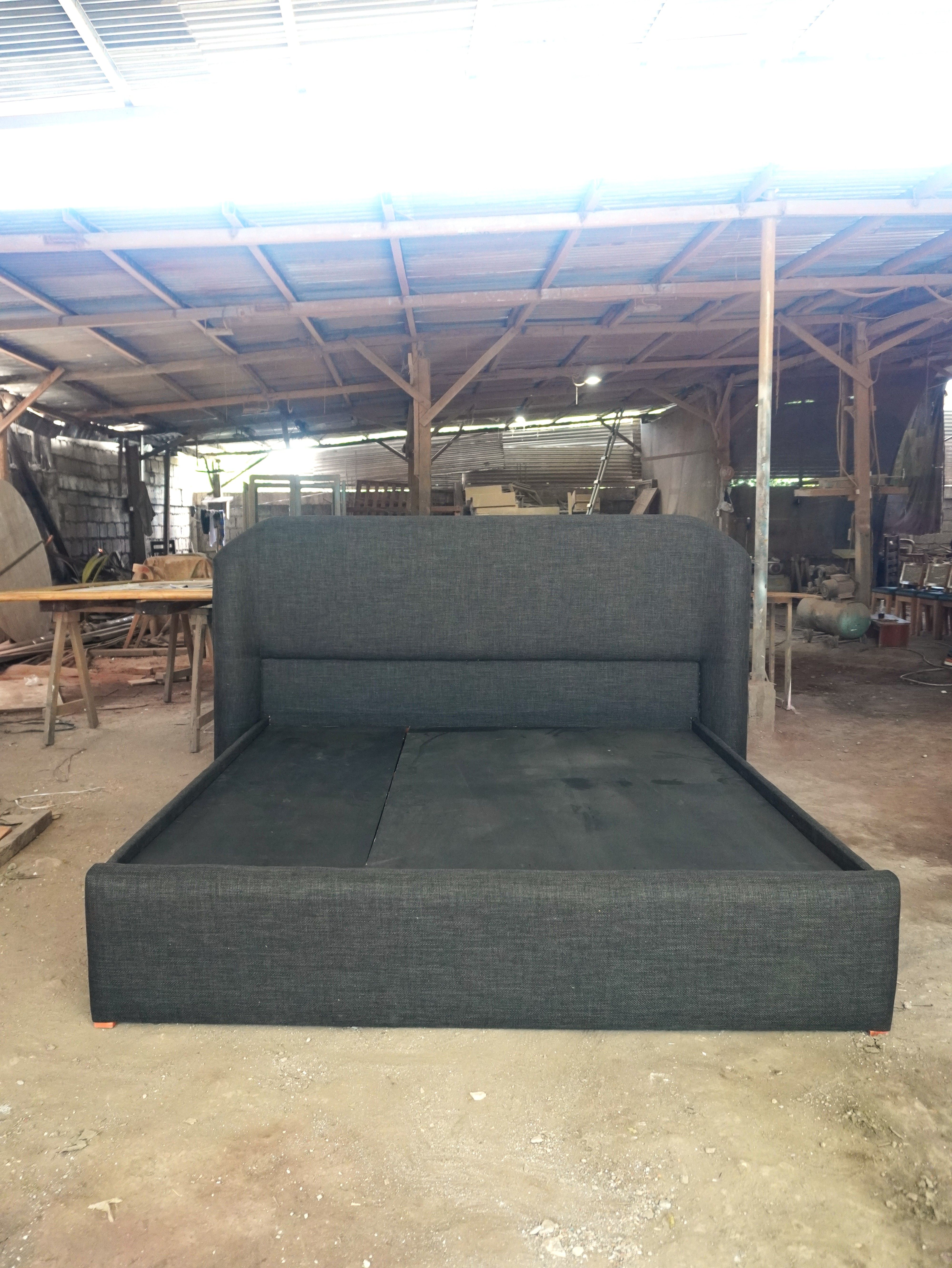 A king-sized upholstered bed in charcoal fabric with a tall, curved headboard, built for a clean, modern bedroom.