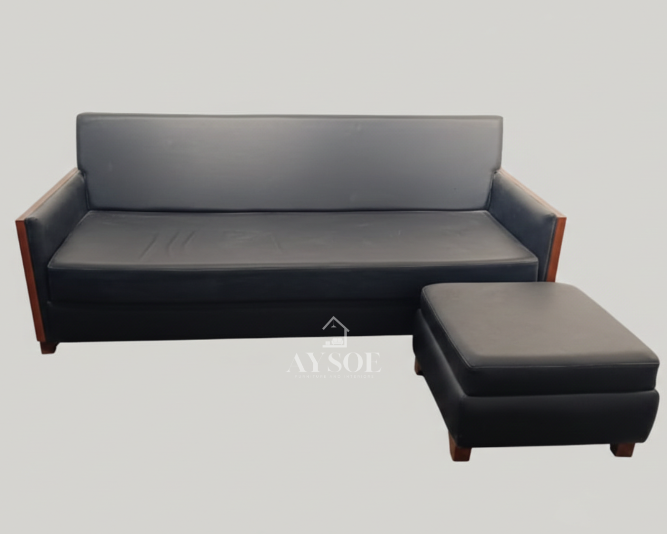 A sleek black leatherette three-seater sofa with cherry wood side panels, wood block legs, and a matching square ottoman. Clean lines, wipe-clean upholstery, made to order.