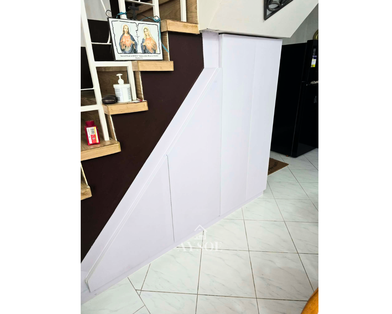 A custom under-stair storage cabinet in a clean white finish, with hinged doors, roomy shelves, and a tall cabinet section. Turns unused stair space into organized storage.