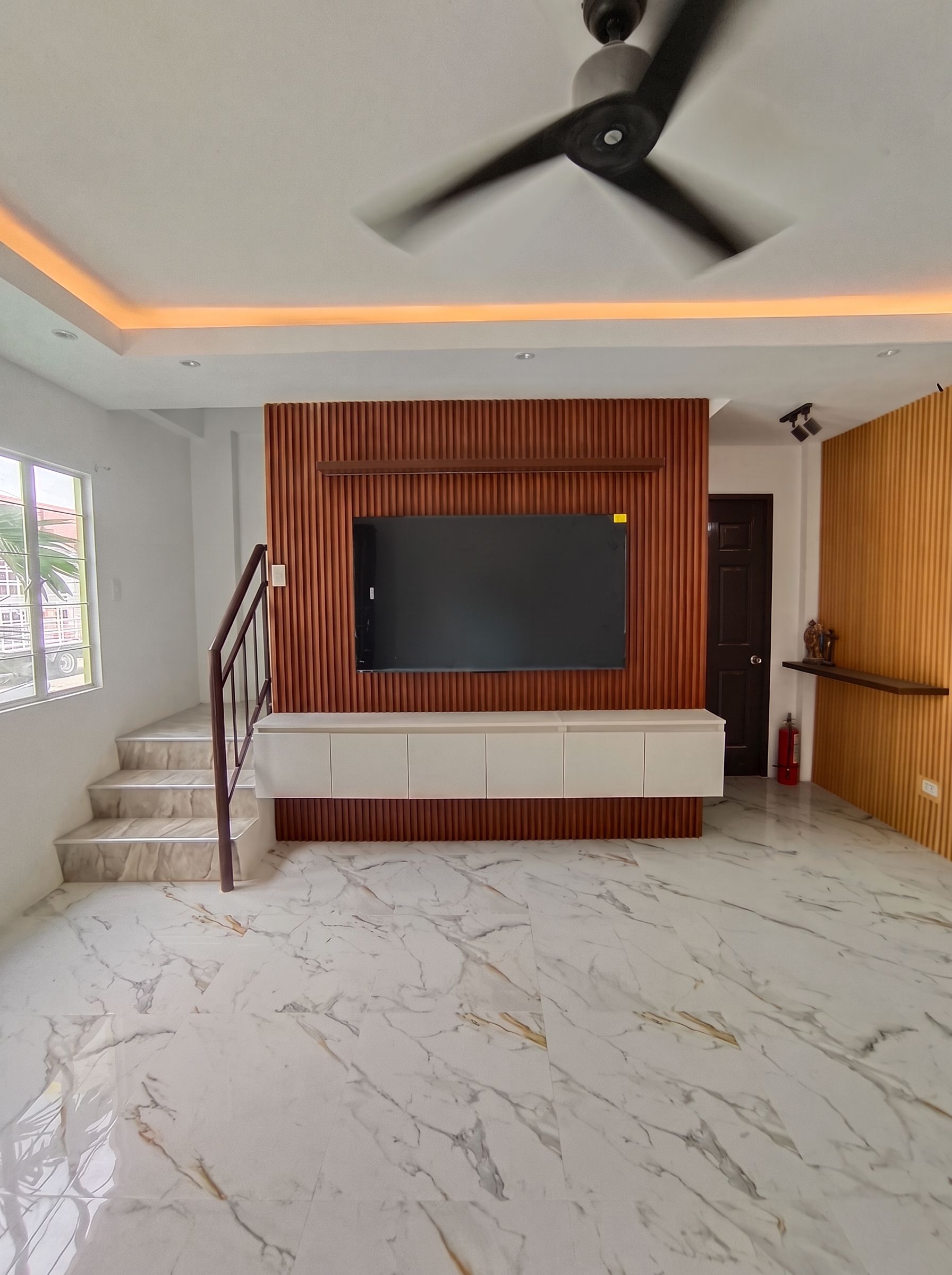 Floating white TV console with a warm slatted wood feature wall and matching accent panel.