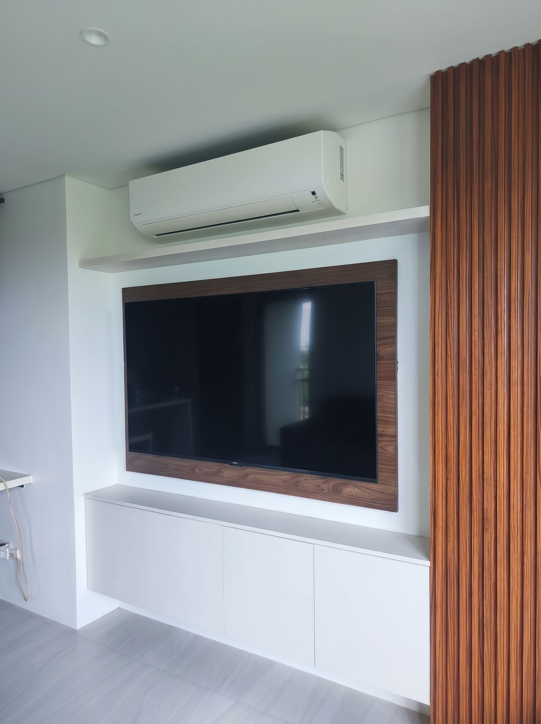 Custom floating TV unit with sleek white cabinetry, wood-finish TV panel, and vertical slat accent wall.