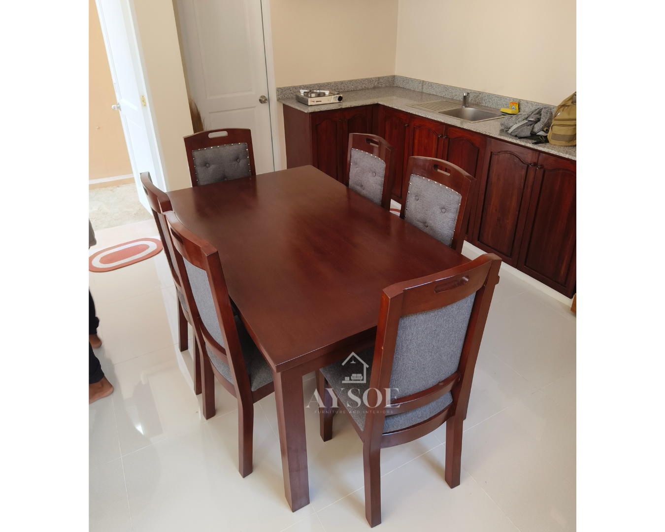 A 6-seater dining set with a solid wood table in a glossy mahogany finish and six upholstered high-back chairs with grey fabric seats and backs. Sturdy, comfortable, made to order.