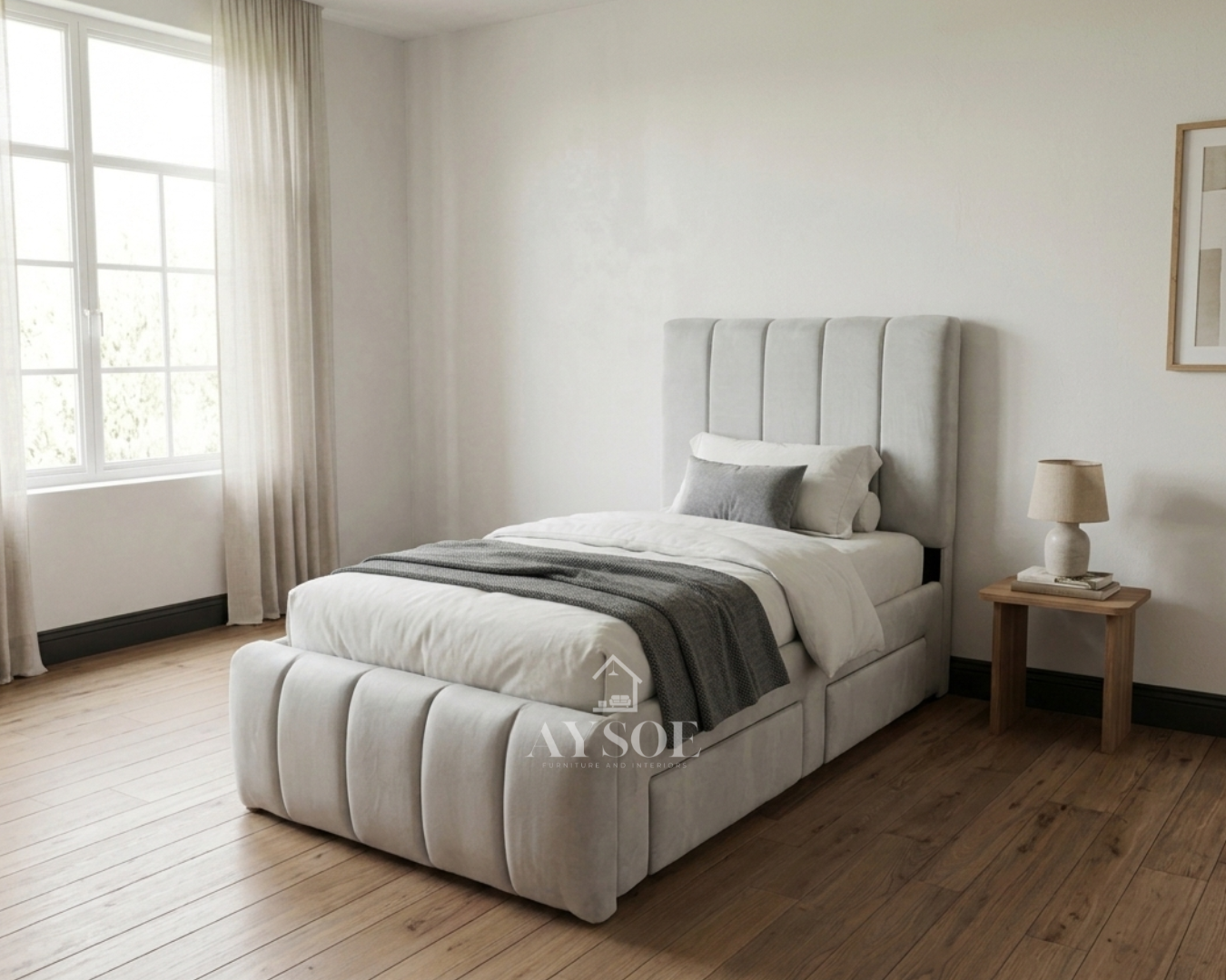 A single bed frame upholstered in soft light grey fabric, with a channel-tufted headboard and footboard and two roomy pull-out drawers. Stylish and space-saving.