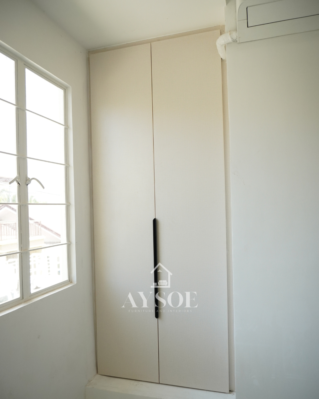A custom bedroom set in a cream linen-texture finish, with a built-in study desk with two drawers and two wardrobes with hanging rods and shelves. Complete storage and a work spot for small rooms.