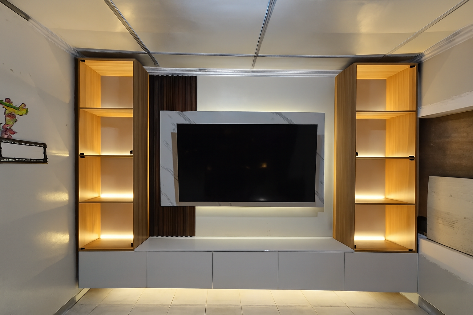 A built-in TV wall with a floating white storage cabinet, a marble-look TV backing panel, a fluted wood accent, and two tall glass-door display towers with warm LED lighting. Made to fit your wall.