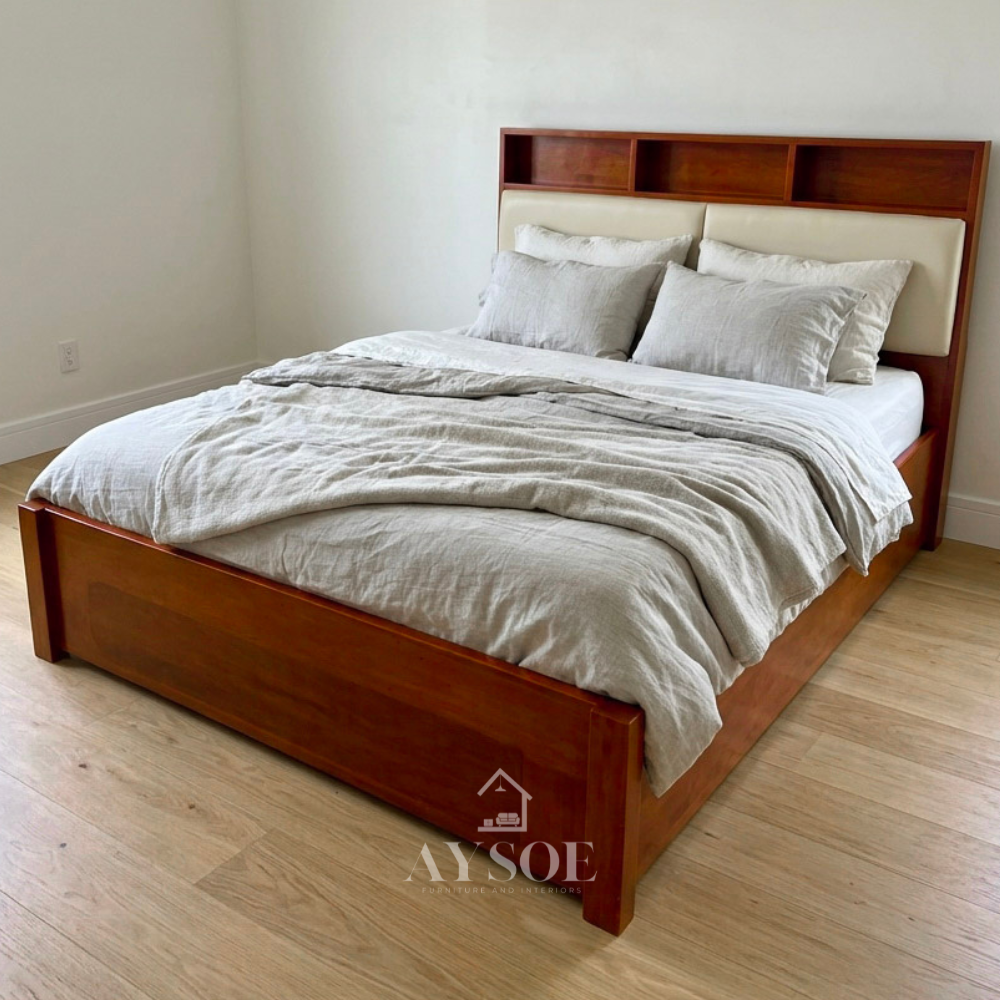 Solid cherry-finish wood bed with a built-in shelf headboard and cream padded back panels. Sturdy frame, warm tones. Available in various sizes, with optional storage or pull-out.