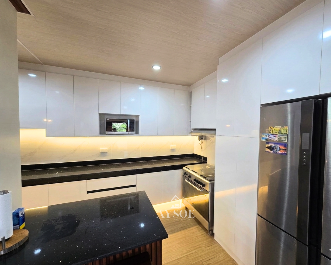 Glossy white kitchen cabinets with a wood bar counter and island. Spacious and stylish.