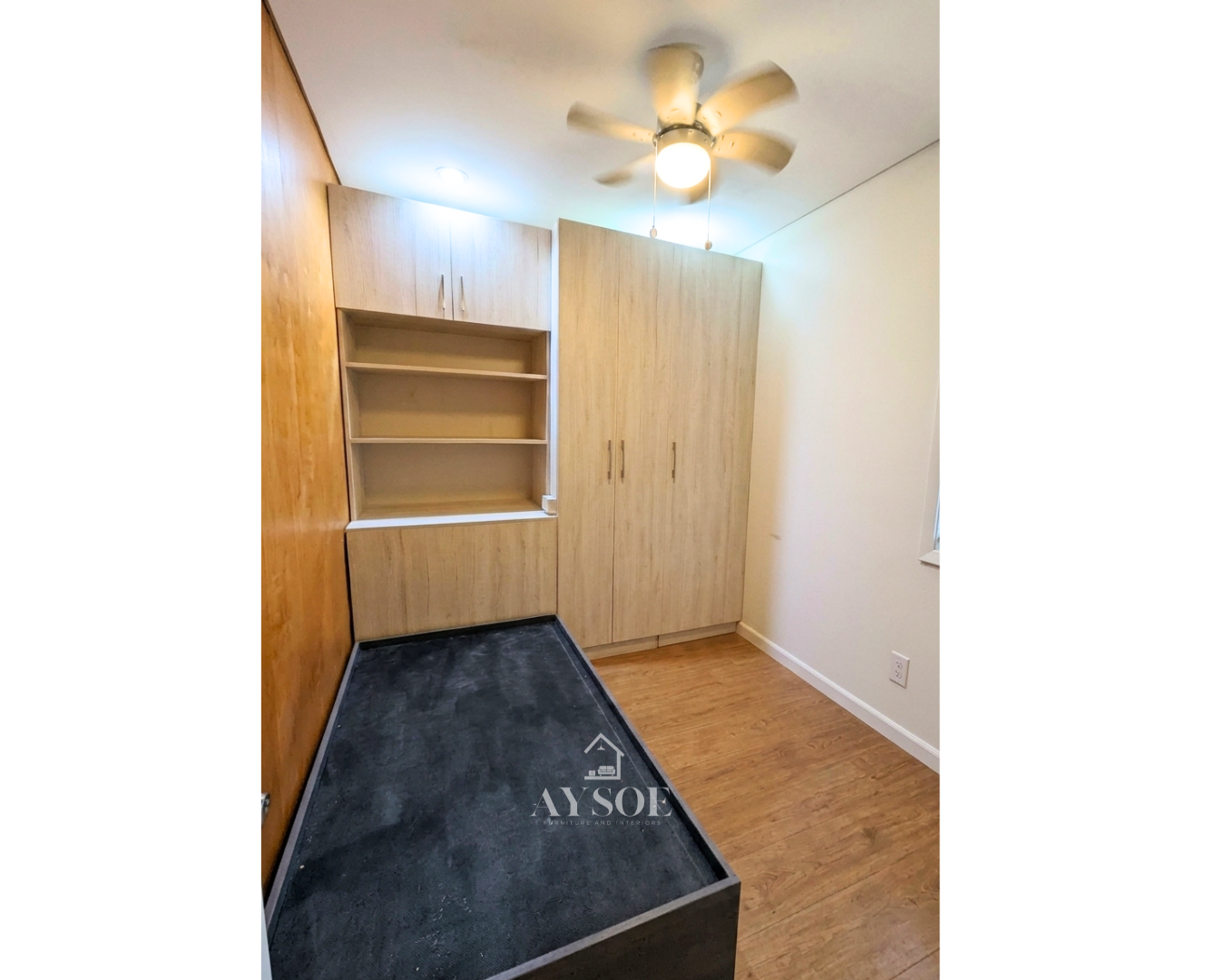 A custom light oak storage set with a tall wardrobe and a built-in shelf unit with overhead and lower cabinets. Smart storage for small rooms.