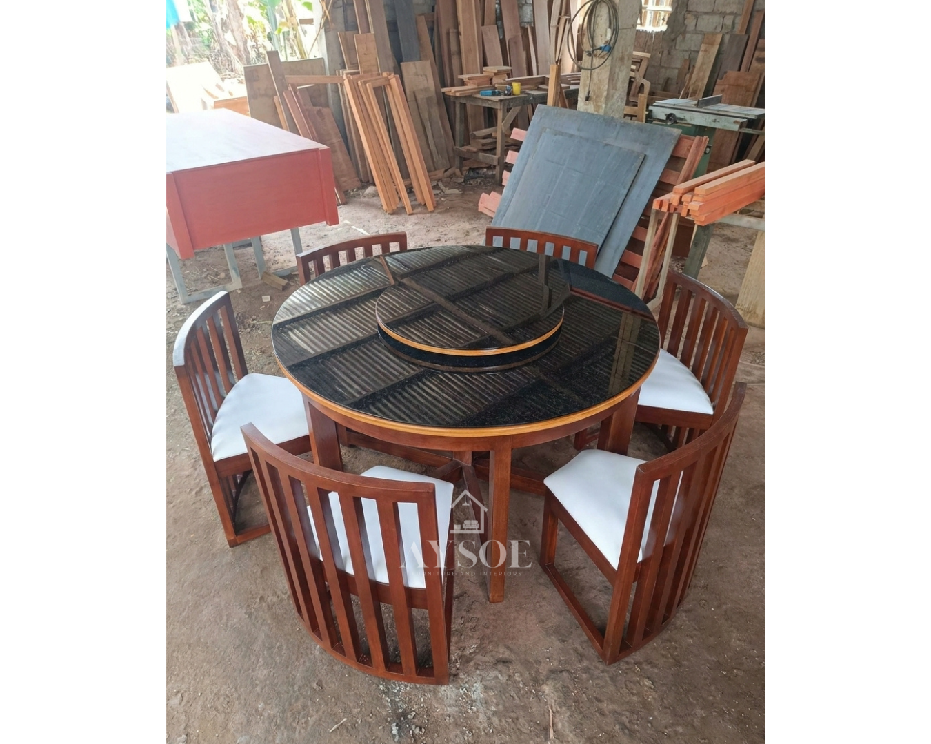 A round 6-seater dining set with a black glass tabletop, a built-in rotating lazy Susan, and six curved slatted-back chairs with white cushioned seats. Solid wood frame, wipe-clean, made to order.