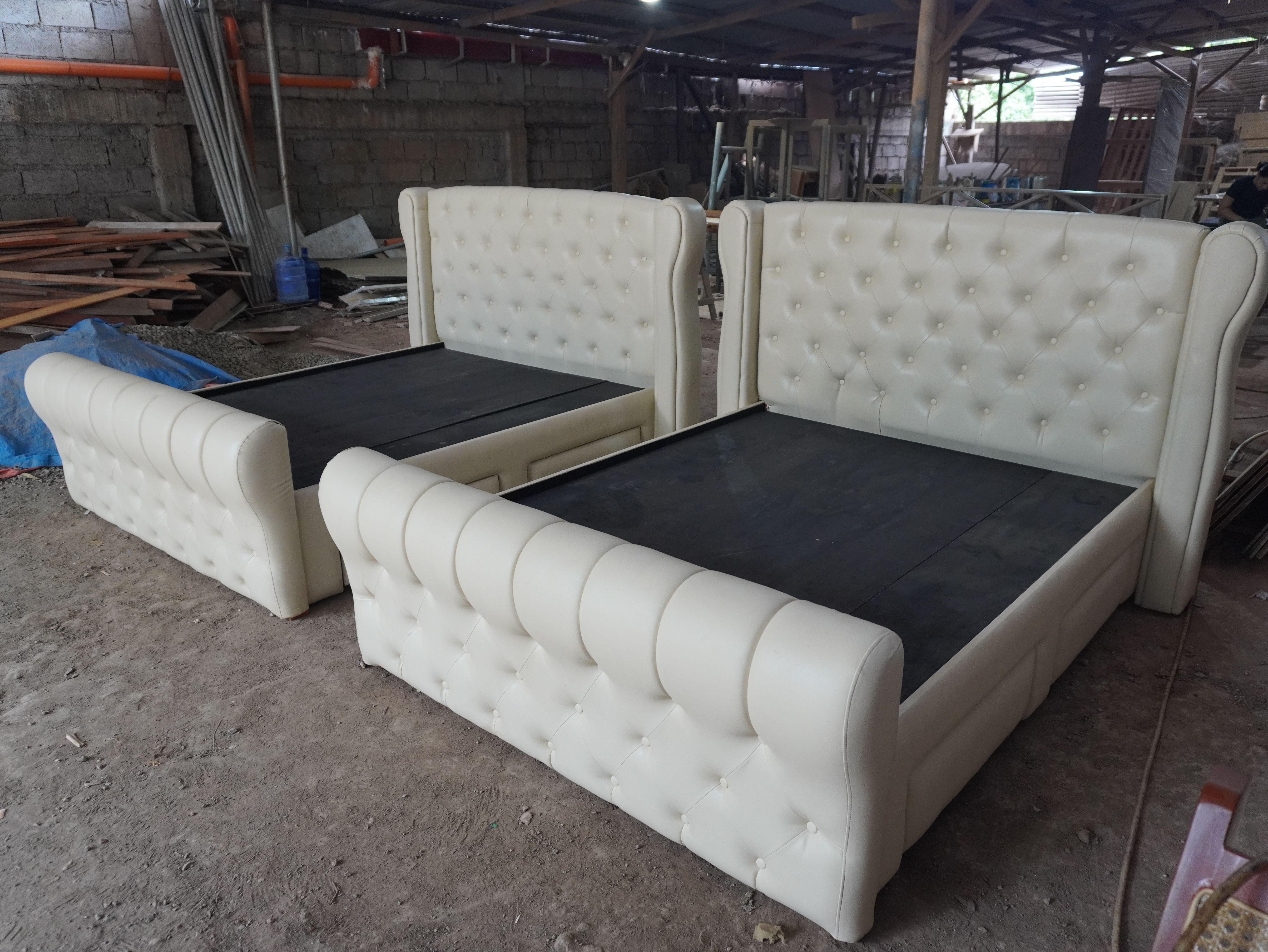 A classic cream leatherette bed with a tall button-tufted wingback headboard, a rolled sleigh footboard, and four built-in side drawers. Elegant, easy to wipe clean, and made to hold a lot.
