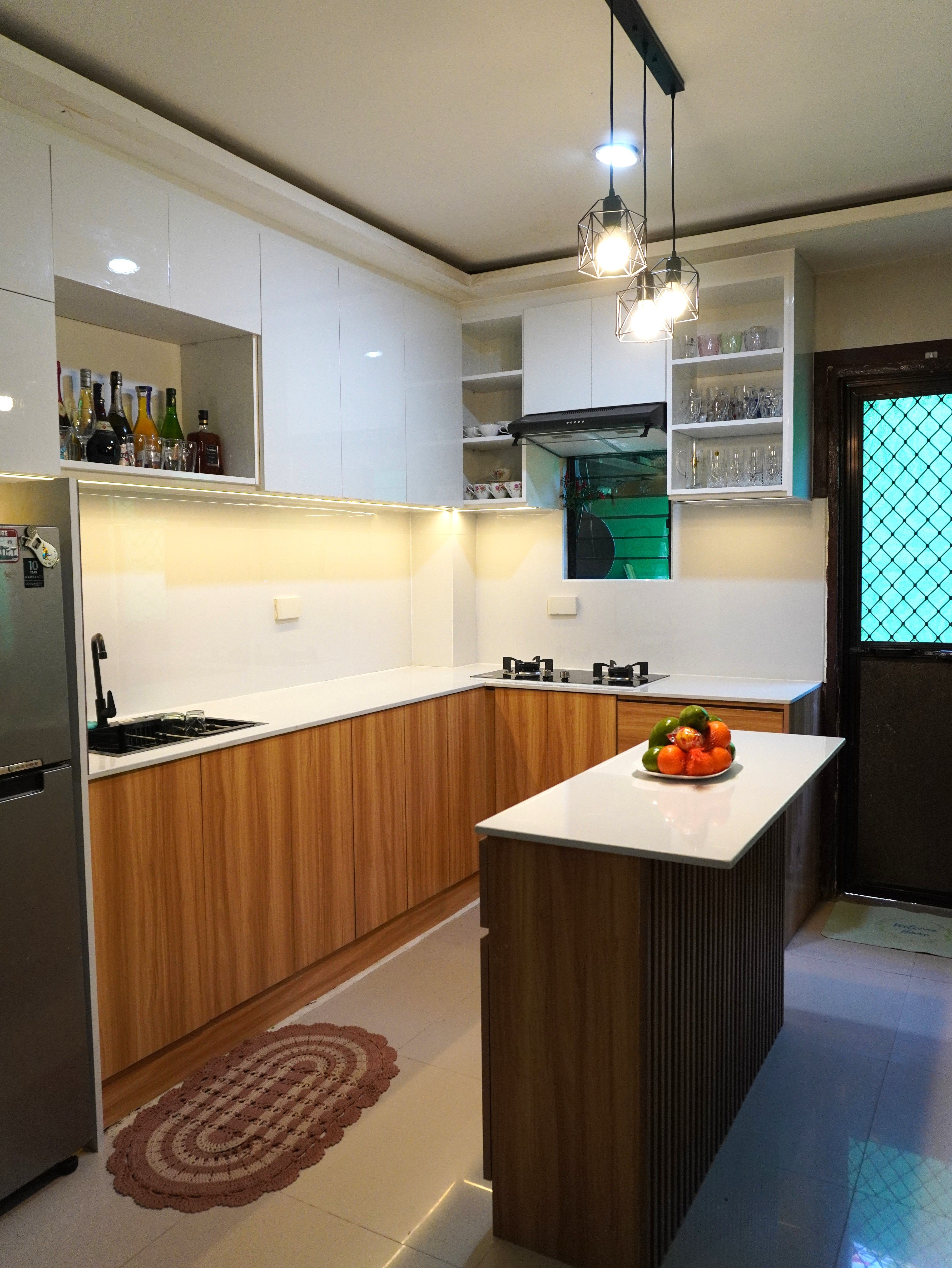 Custom-built kitchen cabinets with glossy white uppers, warm wood-grain base cabinets, and a fluted-panel island, designed for smart storage and a warm, modern look.