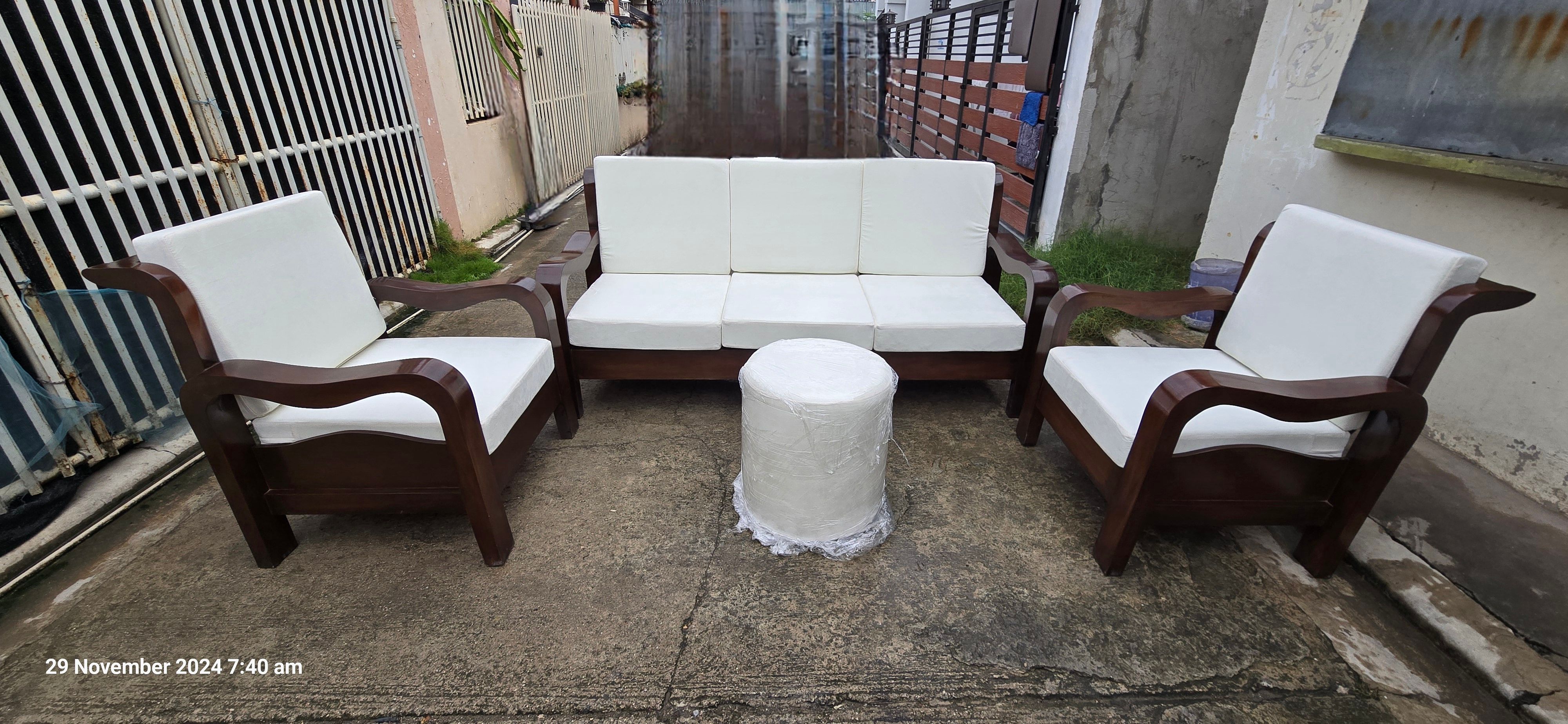 A cylindrical, fully upholstered white round ottoman sits directly in the center, functioning as a modern coffee table or footrest.