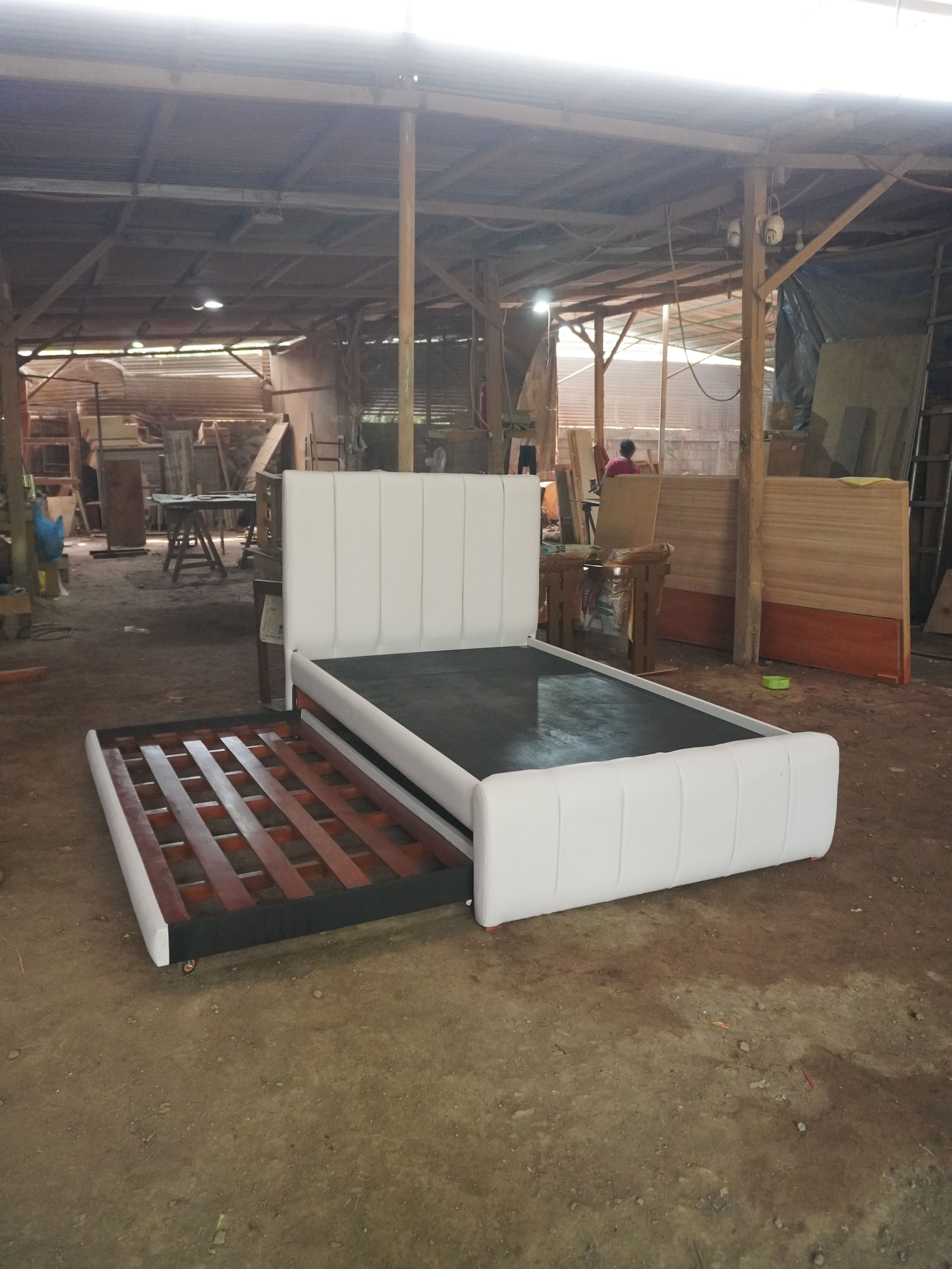 A clean white leatherette bed with a vertical channel headboard and footboard, plus a hidden pull-out bed on wheels. The pull-out can be set to slide out from either the left or right side to suit your room.