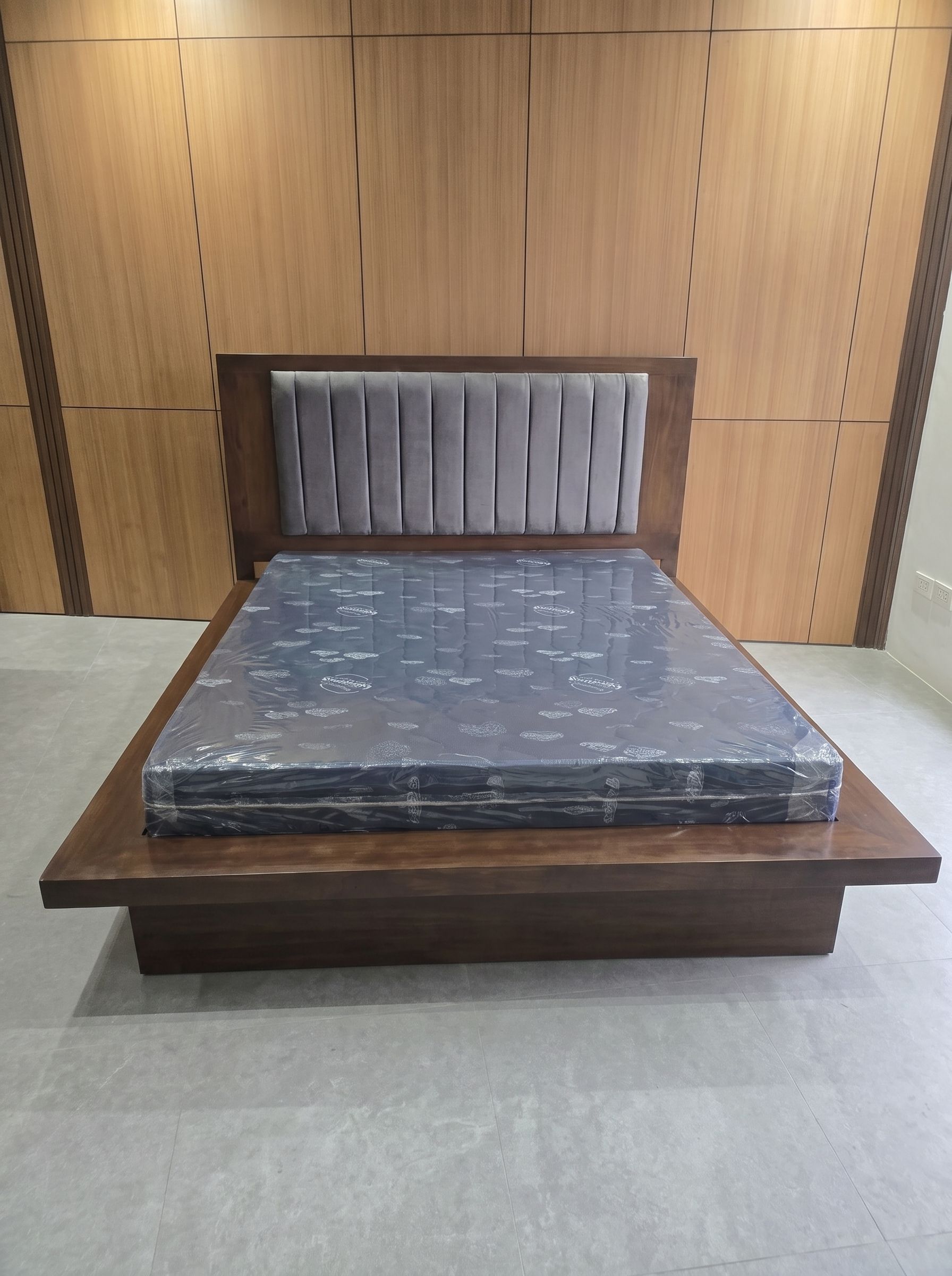 A modern dark walnut platform bed with a wide wood ledge, a recessed base for a floating look, and a tall wood headboard with a soft gray channel-tufted panel. Clean, solid, and built to last.