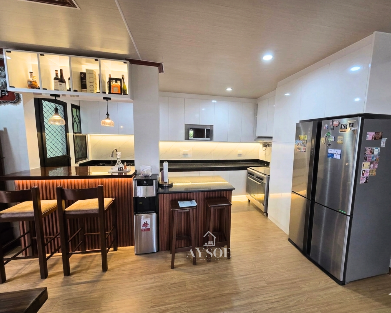 Glossy white kitchen cabinets with a wood bar counter and island. Spacious and stylish.