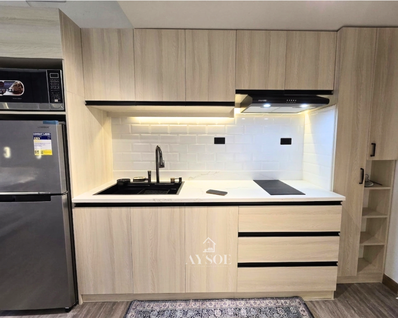 A modern straight kitchen cabinet set in a light oak wood-grain finish, with upper and lower cabinets, three drawers, and a tall pantry tower. Clean, bright, and space-saving.