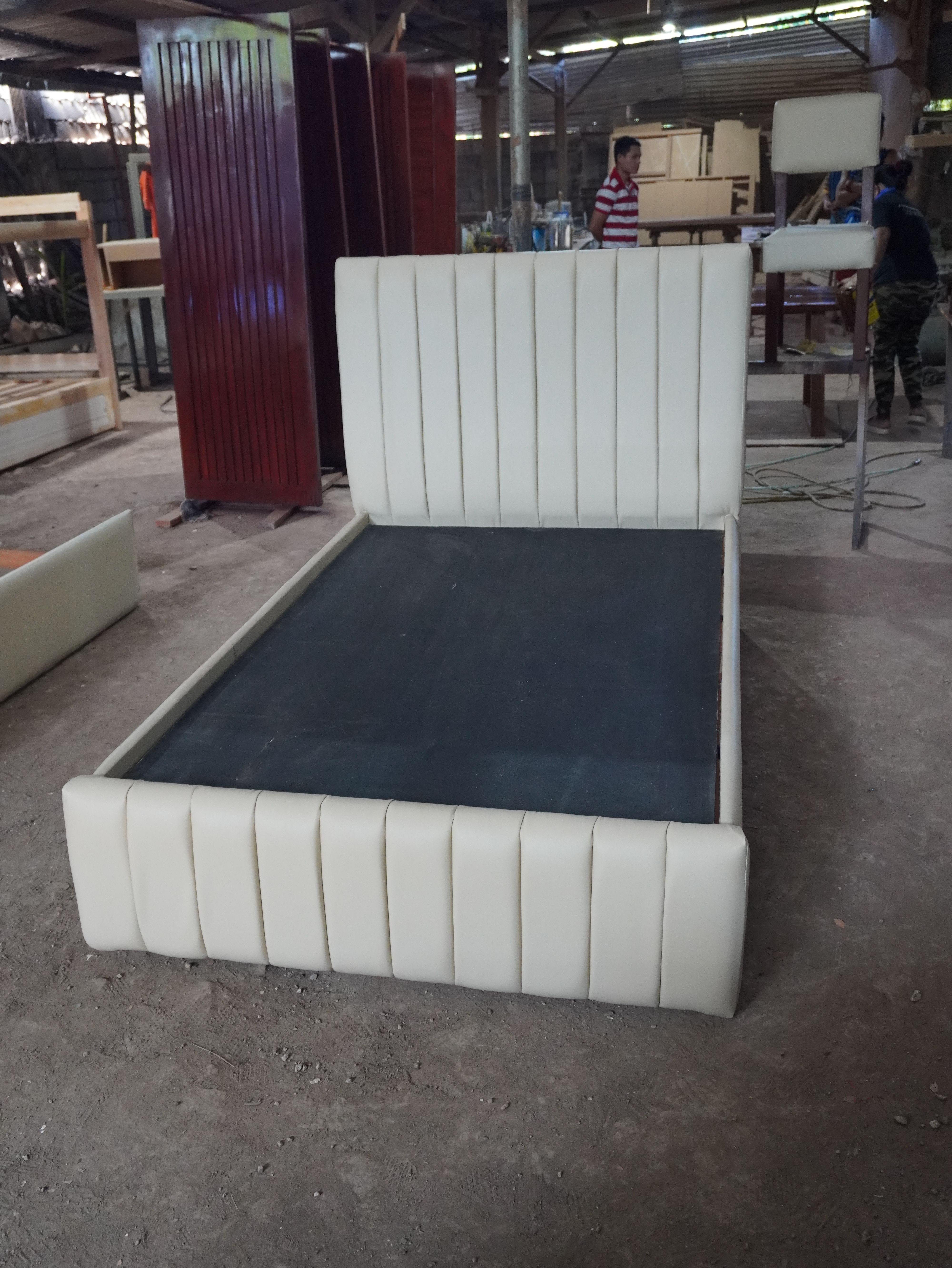 A clean, modern upholstered bed in soft cream leatherette, with vertical channel panels on the headboard and footboard. Fully wrapped frame, easy-to-wipe finish, and a solid platform base.