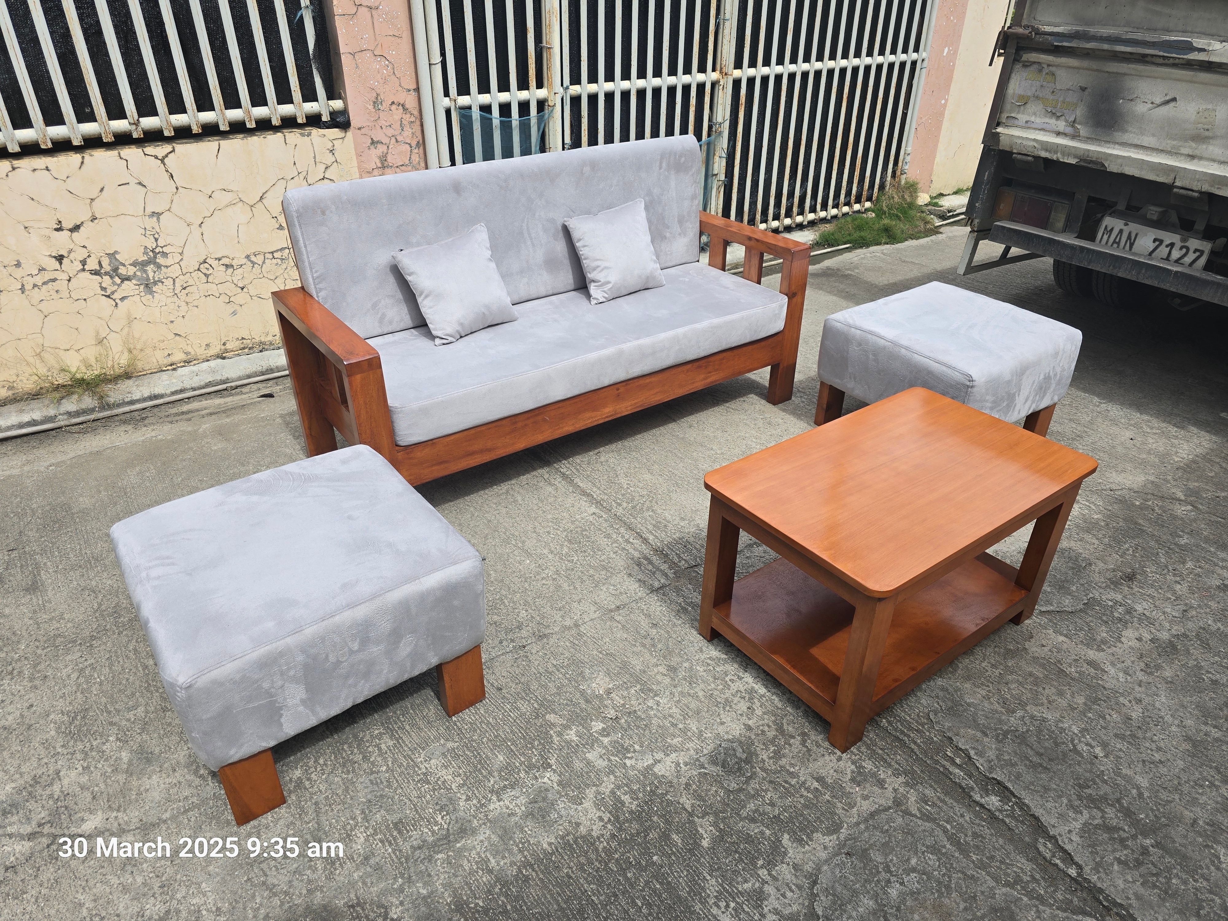 Two matching rectangular ottoman stools with grey fabric tops and wooden legs are positioned on either side of the layout.