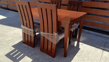 Four matching wooden chairs with vertical slat-back designs, straight legs, and warm mahogany-brown finishes.