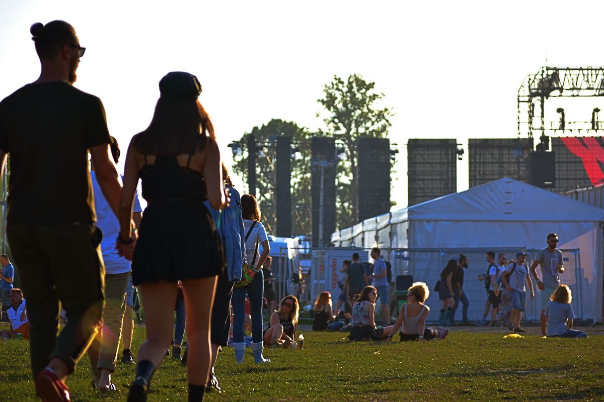 Festivalgoers gathered near a stage at a daytime outdoor music festival