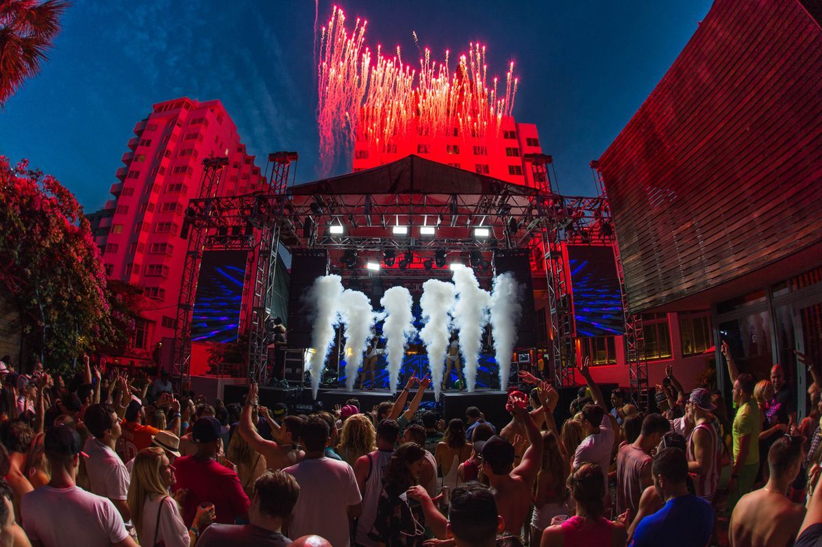 A large music festival crowd watching a stage with lights and fireworks