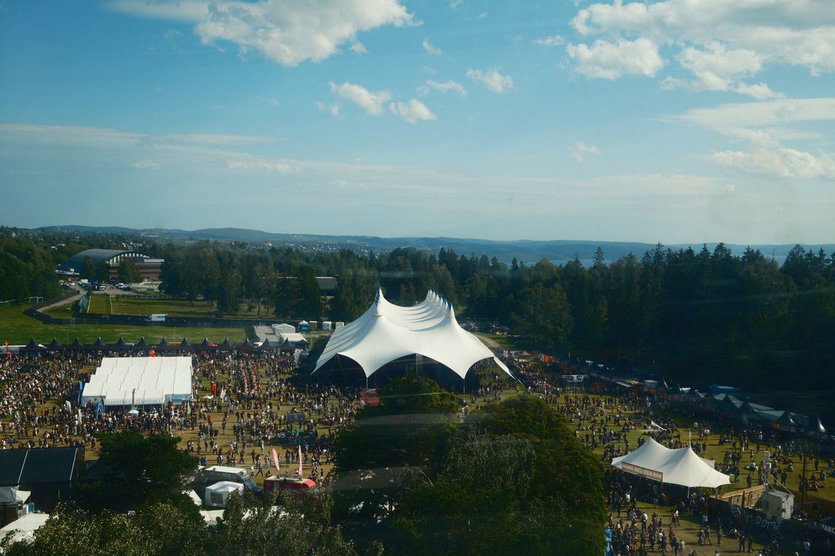 An aerial view of outdoor music festival grounds with a crowd and tents