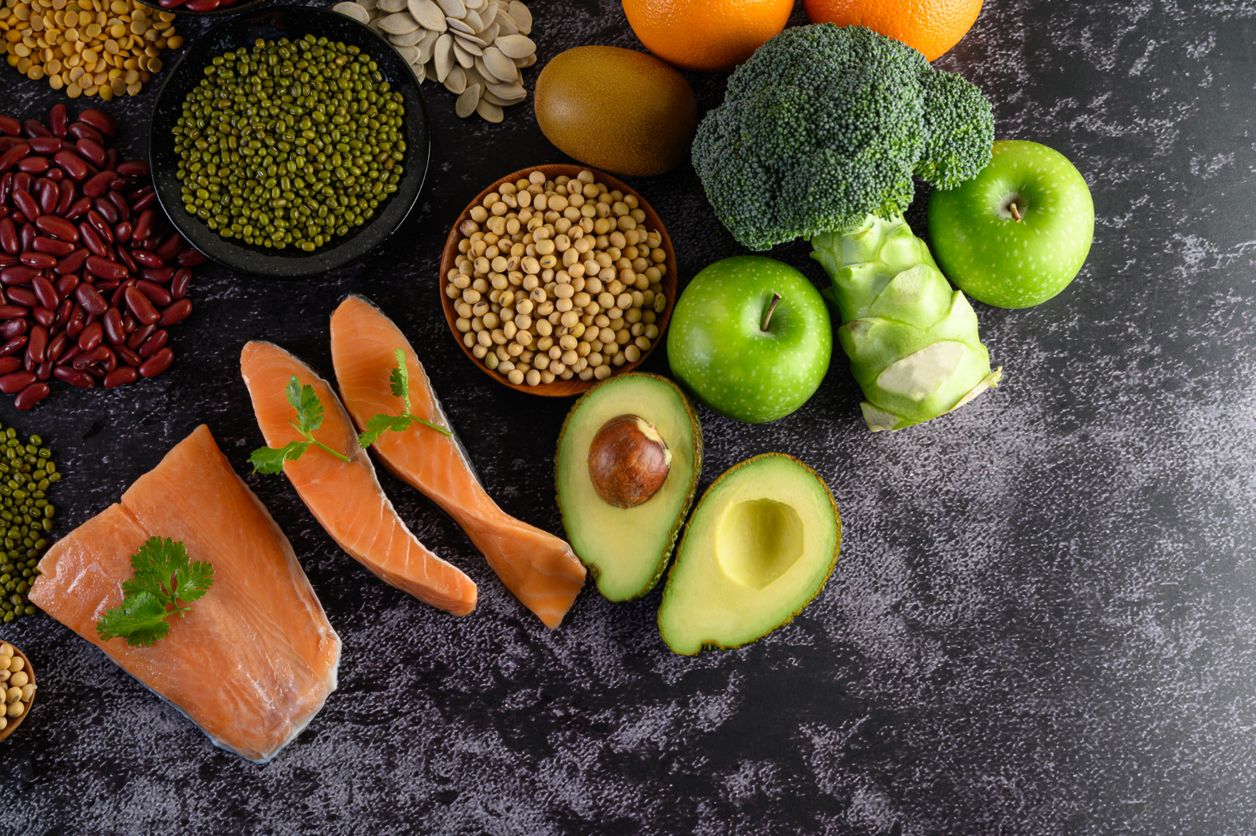 Salmón, aguacate, brócoli, manzanas verdes y legumbres sobre una superficie oscura