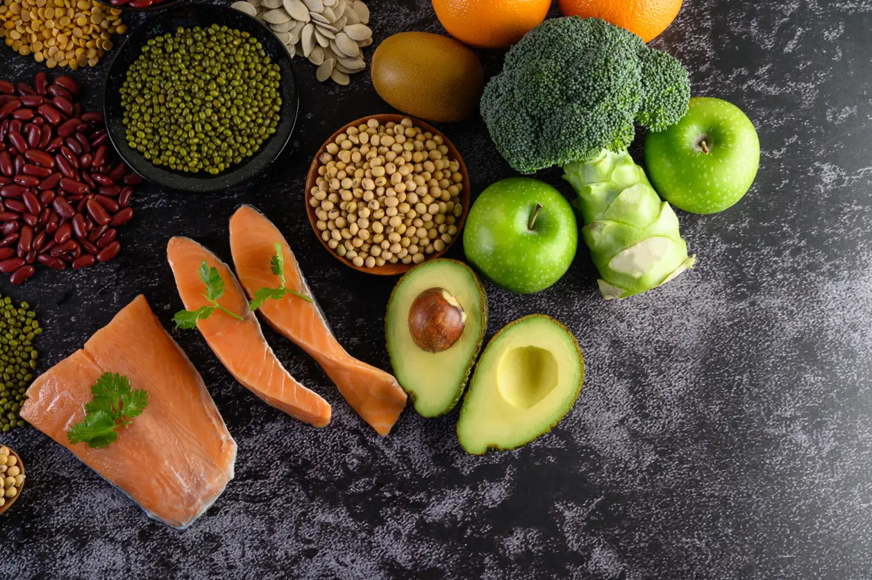 Salmón, aguacate, brócoli, manzanas verdes y legumbres sobre una superficie oscura