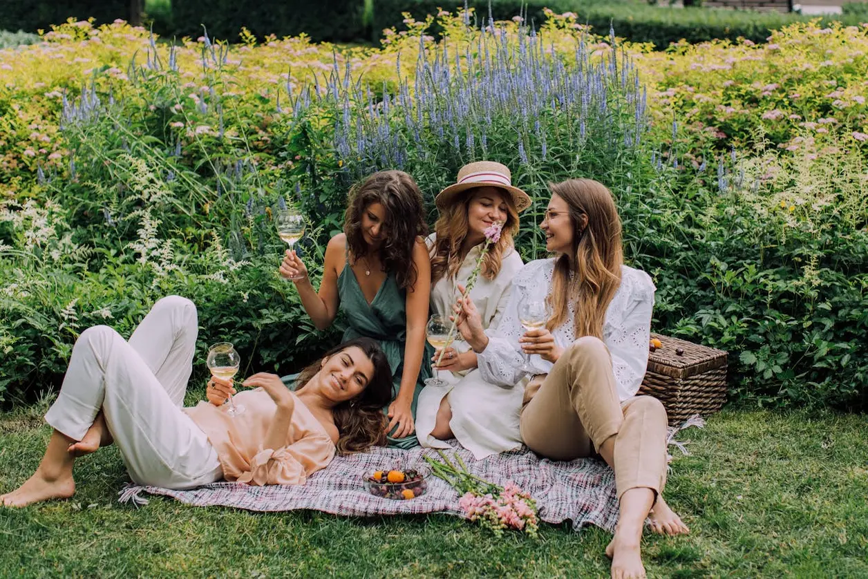 Tres amigas brindan sentadas en la hierba durante un picnic