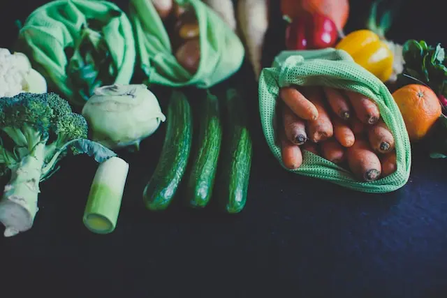 Verduras y frutas en bolsas de malla reutilizables sobre una mesa oscura