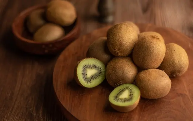 Kiwis enteros y partidos sobre una tabla de madera