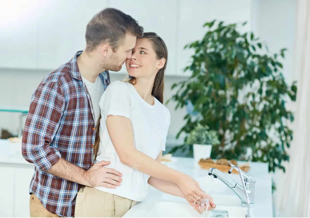Pareja se abraza sonriendo en la cocina