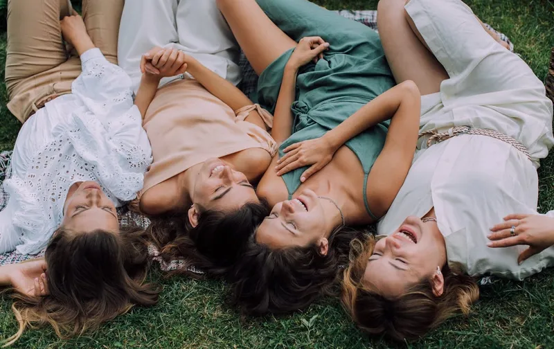 Cuatro amigas tumbadas en la hierba riendo