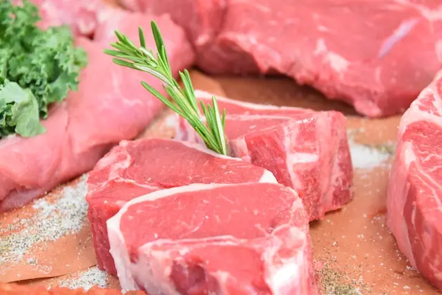 Cortes de carne roja cruda con una ramita de romero