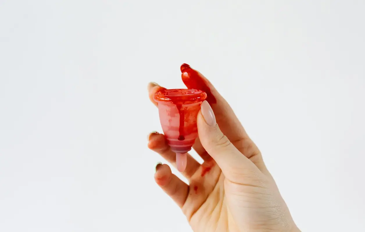 Mano sostiene una copa menstrual con sangre