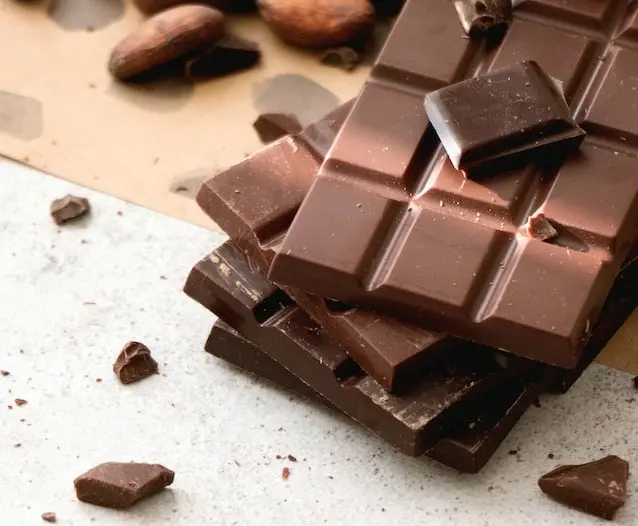 Tabletas de chocolate negro troceadas junto a granos de cacao