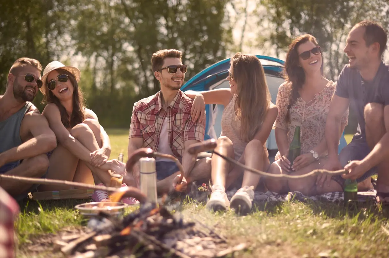 Grupo de amigos ríe alrededor de una hoguera de camping